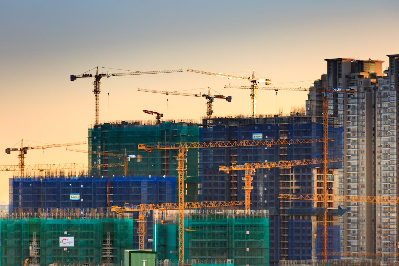 gallery-6 A cityscape featuring high-rise buildings under construction with cranes during sunset.