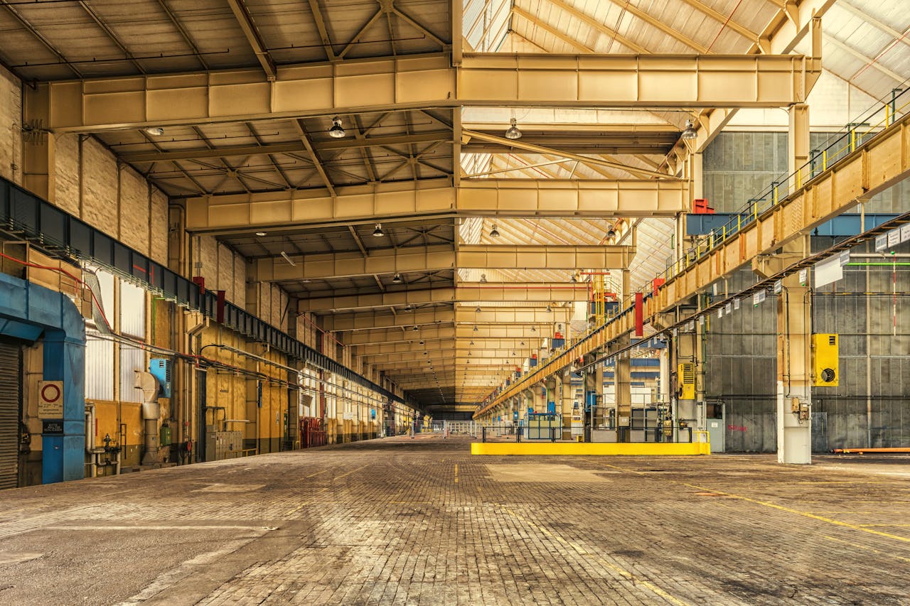 our-services-1 Expansive interior of an industrial warehouse showing steel beams, high ceilings, and ample space.