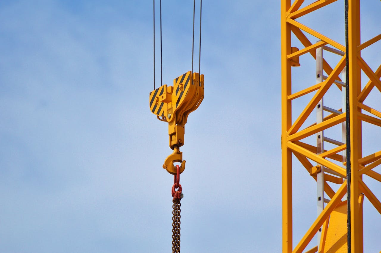 our-services-3 Close-up of a yellow crane arm against a clear blue sky, showcasing industrial equipment.